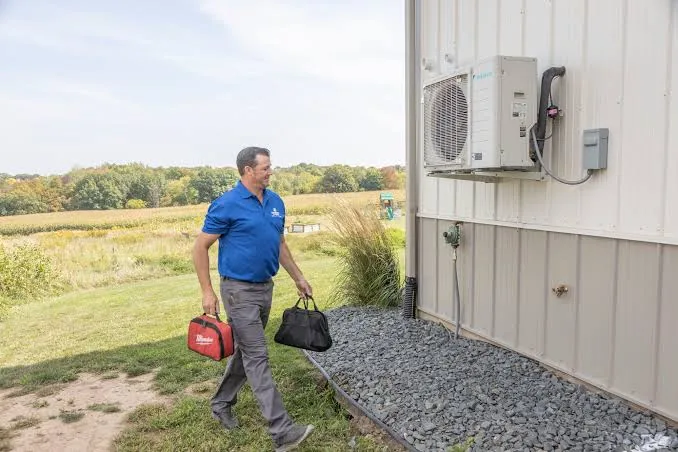 Outdoor mini-split condenser on a home wall with open landscape nearby