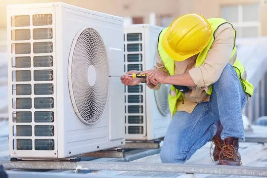 Rooftop air conditioning condensers being inspected with a screwdriver